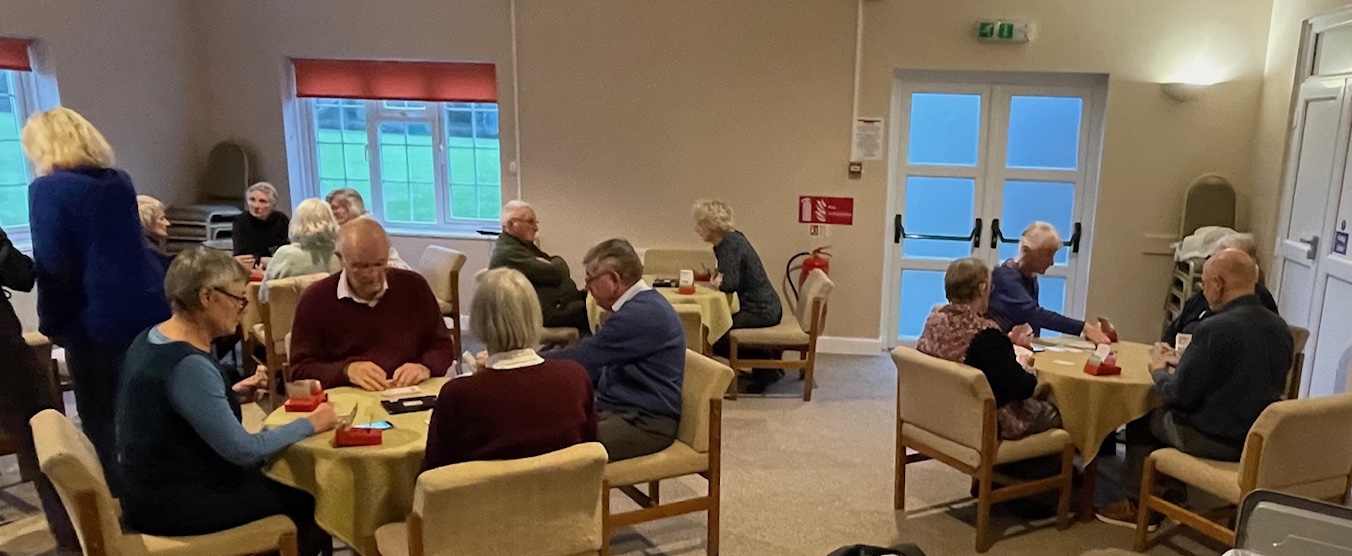 Room showing tables of people playing bridge